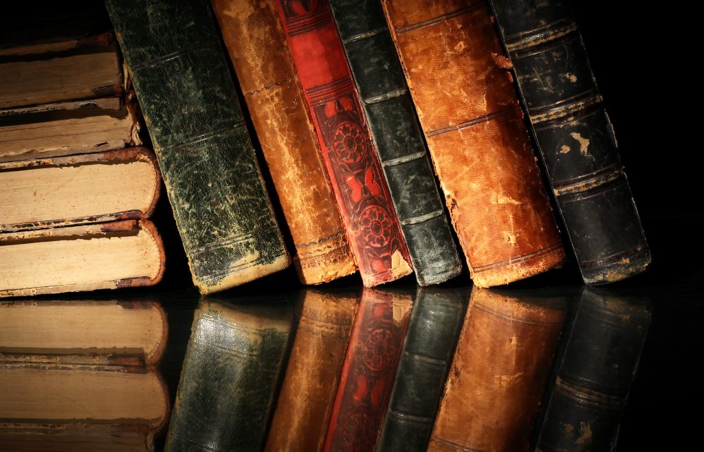 Set of various old books on dark background with reflection